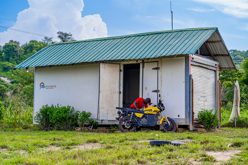 Man inspecting motorbike next to a small building